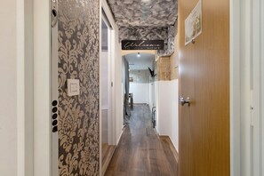 Ein Flur mit Wandpapier mit Muster, einer Holztür und einem Willkommensschild.