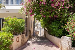 A narrow alleyway with a gate, flanked by lush greenery and flowering plants. - Villa Nadezda – 3-Bedroom Villa with Pool near Paphos Harbour (Pafos)
