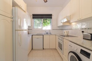 A compact kitchen with white cabinetry, a dishwasher, a washing machine, and a microwave. - Villa Nadezda – 3-Bedroom Villa with Pool near Paphos Harbour (Pafos)