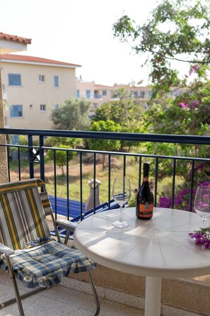 A balcony with a table, a chair, a bottle of wine, and a glass. - Villa Nadezda – 3-Bedroom Villa with Pool near Paphos Harbour (Pafos)