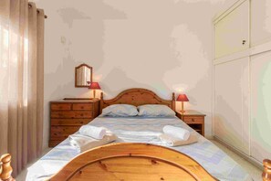 A bedroom with a wooden bed, two bedside tables with lamps, a dresser, and a wardrobe. - Villa Nadezda – 3-Bedroom Villa with Pool near Paphos Harbour (Pafos)
