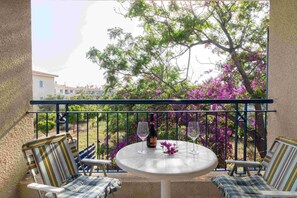 A balcony with a table, two chairs, and a bottle of wine. - Villa Nadezda – 3-Bedroom Villa with Pool near Paphos Harbour (Pafos)