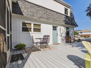 Une maison avec un porche couvert, une table à manger avec des chaises et une porte.