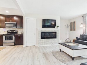 A modern living room with a fireplace, a flat-screen TV, and a sofa. - `The Harlow`- The Cottage Collection (Virginia Beach)