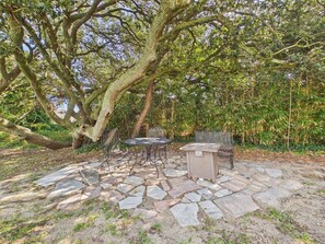 Un espace extérieur aménagé avec un sol en pierre, une table ronde et un chauffage intégré.