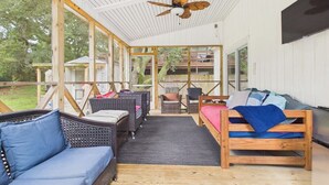 An open-plan living area with a ceiling fan, wicker furniture, and a wooden bed. - `The Harlow`- The Cottage Collection (Virginia Beach)