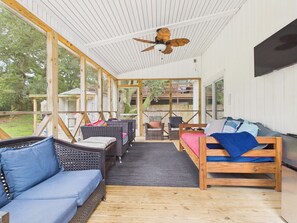 An open-plan living area with a ceiling fan, wicker furniture, and a wooden bed. - `The Harlow`- The Cottage Collection (Virginia Beach)