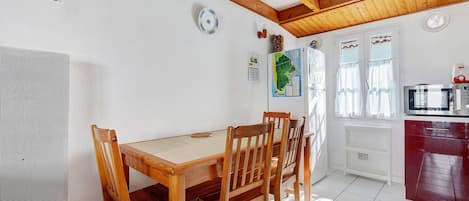 Un comedor con mesa y sillas de madera, una cocina con refrigerador y microondas, y un mapa en la pared.