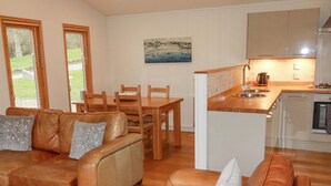 Una sala acogedora con sofá y sillones, una mesa de comedor y una cocina con fregadero y estufa.