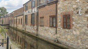 Un edificio histórico con fachada de piedra y varias ventanas, junto a un canal.