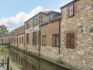 A historic building with a stone facade and multiple windows, adjacent to a canal. - Glass House (Blandford Forum)