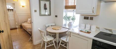Una cocina con una mesa, sillas, estufa y ventana con una planta.