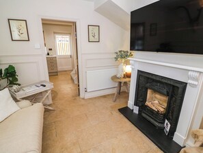 Ein Wohnzimmer mit Kamin, Fernseher und einer Tür zu einem anderen Raum.