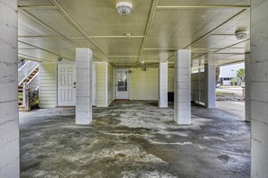 A covered parking area with concrete pillars, a concrete floor, and a door leading to a building. - Luna May - Charming 2 Bedroom, 3 Bath Beach House (Garden City Beach)