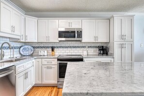 A modern kitchen with white cabinets, a microwave, a toaster, and a coffee maker. - Royal Garden 1115 - 2 Bed 2 Bath Luxury Condo with Ocean and Marsh Views! (Garden City Beach)