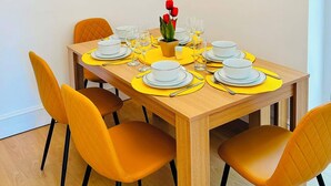 Ein Essbereich mit einem Holztisch, gedecktem Platz für vier Personen, gelben Platzsets und orangefarbenen Stühlen.