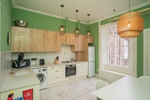 Eine Küche mit Holzausstattung, einer Waschmaschine, einer Mikrowelle und einem Kühlschrank.