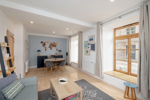 A modern living room with a dining area, a large window with curtains, and a view of the street. - Historic Whisky Bond 2BR | Free Parking - Pass the Keys (Edinburgh)