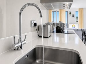 Eine moderne Küche mit Spüle aus Edelstahl, einem Wasserhahn und einem Wasserkocher.