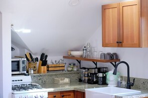 A kitchen with a gas stove, microwave, and various kitchen utensils and appliances. - Carriage House at Historic Chapman House Arcata (Arcata)