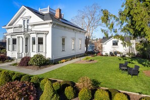 Une maison blanche à deux étages, dotée d’un porche à l’avant et d’une pelouse bien entretenue.