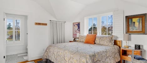 Une chambre à coucher avec un grand lit, une table de chevet, une lampe, une chaise, une fenêtre et une porte.
