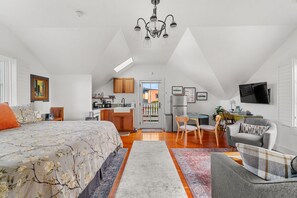 A spacious loft bedroom with a large bed, a kitchenette, and a dining area. - Carriage House at Historic Chapman House Arcata (Arcata)