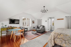 A spacious loft bedroom with a large bed, a desk, and a dining area. - Carriage House at Historic Chapman House Arcata (Arcata)