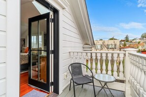 Ein Balkon mit Glastür zu einem Zimmer, einem Stuhl und einem kleinen Tisch.