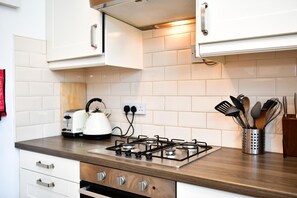 A modern kitchen with a gas stove, a kettle, and a utensil holder on the countertop. - Charming Apartment in the Heart of Llandaff - Pass the Keys (Cardiff)