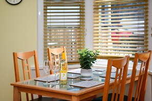 A dining table with chairs, a bottle of wine, and a potted plant. - Charming Apartment in the Heart of Llandaff - Pass the Keys (Cardiff)