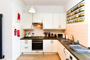 A modern kitchen with white cabinets, a gas stove, a microwave, and a sink. - Charming Apartment in the Heart of Llandaff - Pass the Keys (Cardiff)