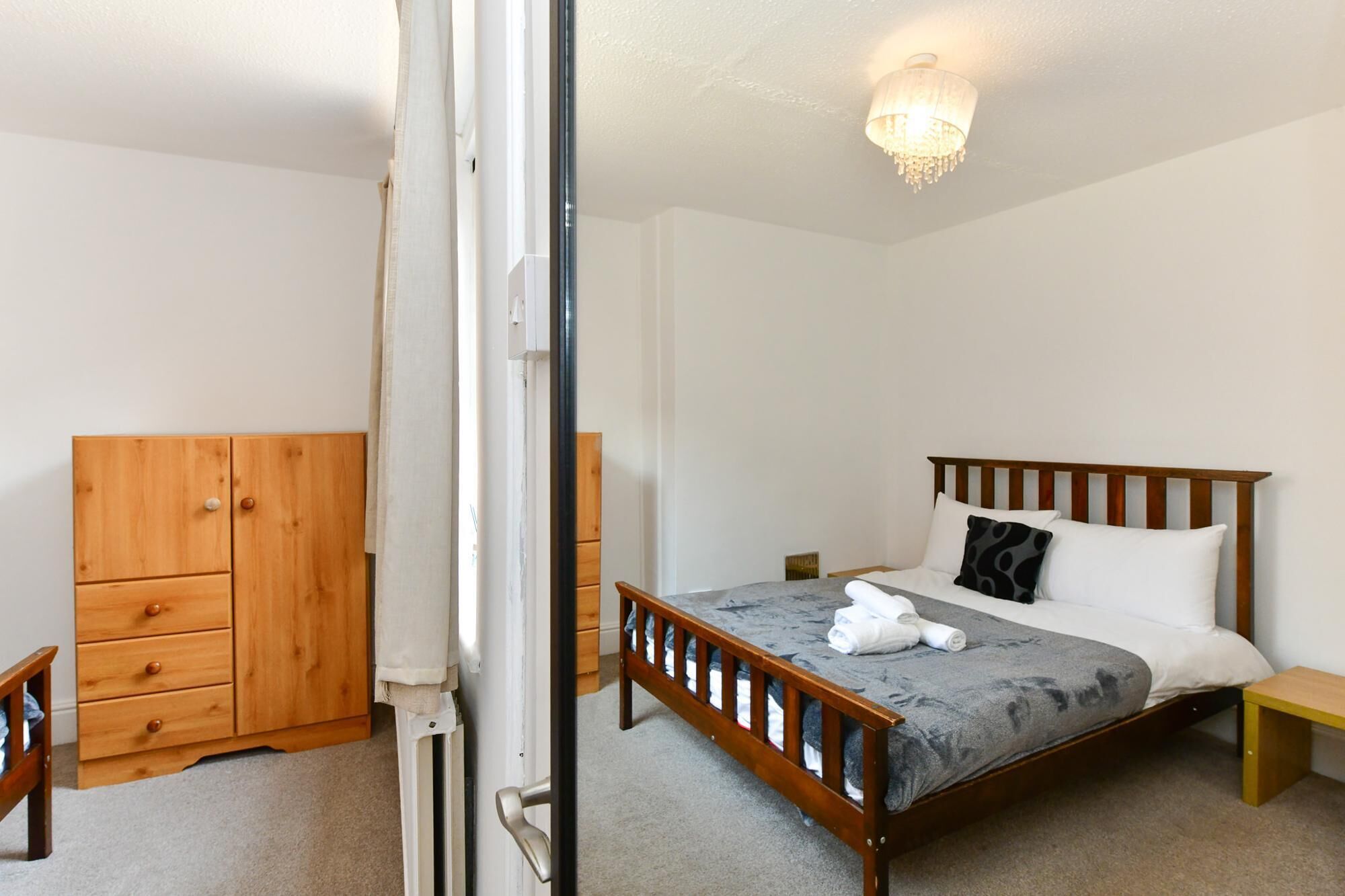 A bedroom with a wooden bed, a wooden wardrobe, and a small bedside table.