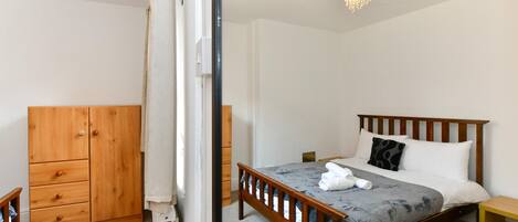 A bedroom with a wooden bed, a wooden wardrobe, and a small bedside table.