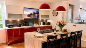Una cocina moderna con una isla central, armarios rojos y un televisor de pantalla plana sobre la isla.