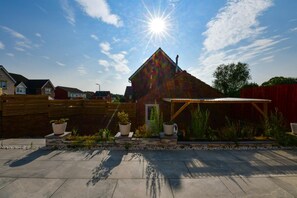 Ein Wohnhaus mit Satteldach, überdachter Terrasse und Garten mit Kübelpflanzen.