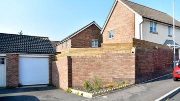 A residential building with a garage, a brick wall, and a small garden area.