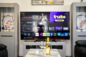 Ein Flachbildfernseher an der Wand, der über eine digitale Oberfläche verschiedene Streaming-Dienste und Sender anzeigt.