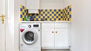 Pequeña lavandería con lavadora, lavamanos y salpicadero de azulejos.