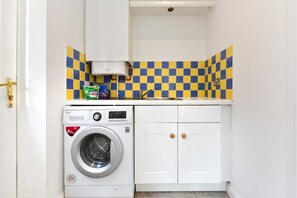 A compact laundry room with a washing machine, a sink, and a tiled backsplash. - Spacious Family Home | Free Parking | Sleeps 6 - Pass the Keys (Cardiff)