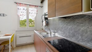 A compact kitchen with a window, a sink, and a stove. - Vacation Home 'Appartamento A Costarainera' with Sea View, Wi-Fi, and Air Conditioning (Pantai)