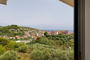 Une ville côtière avec des bâtiments construits sur une colline, un ciel dégagé et la mer à l’horizon.