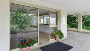 A hotel entrance with a glass door, a potted plant, and a doormat. - Vacation Home 'Appartamento A Costarainera' with Sea View, Wi-Fi, and Air Conditioning (Pantai)