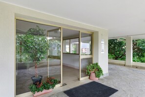A hotel entrance with a glass door, a potted plant, and a doormat.