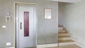 A hallway with a door, a staircase, and a notice board. - Vacation Home 'Appartamento A Costarainera' with Sea View, Wi-Fi, and Air Conditioning (Pantai)