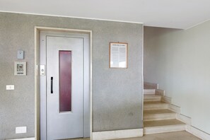 A hallway with a door, a staircase, and a notice board.