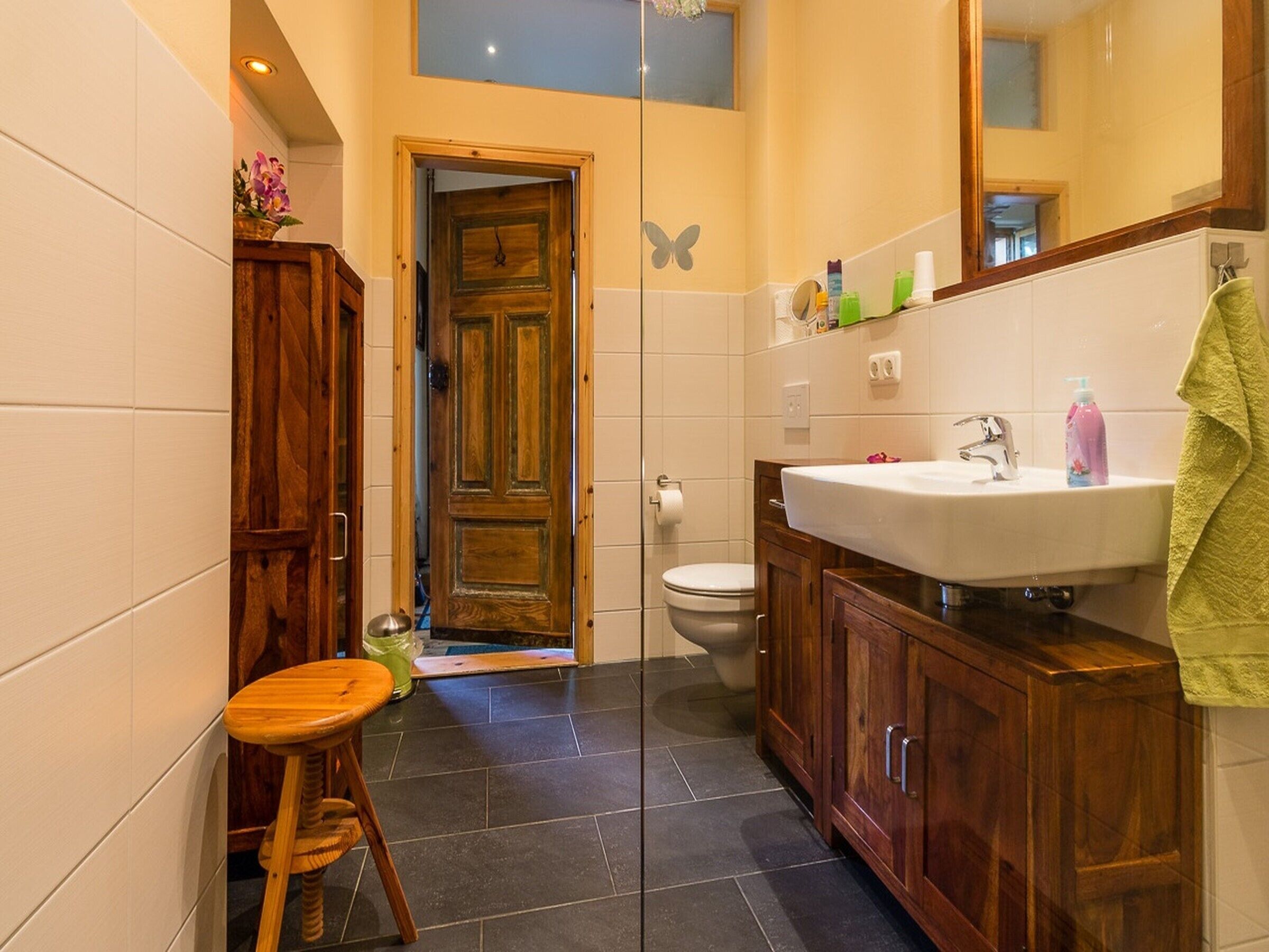 A bathroom with a wooden door, a white sink, and a mirror.