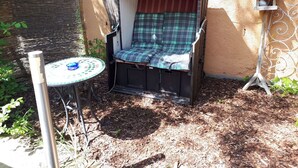 A small outdoor seating area with a metal chair and table, a decorative lantern, and a wall with a textured surface. - Apartment 'Romantika 3' with Shared Pool, Shared Garden and Wi-Fi (Potsdam)