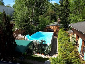 Patio trasero con piscina, rodeado de árboles y un cobertizo pequeño.