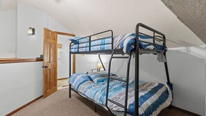 A bunk bed room with a door, a lamp, and a wall-mounted light fixture. - Lake of the Ozarks Villa — Pool, Dock & Minutes to Shopping (Osage Beach)